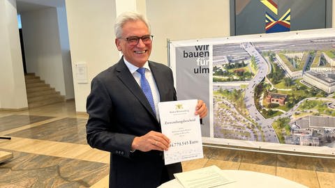 Ulms Oberbürgermeister Gunther Czisch hält den Förderbescheid des Landes hoch. Er freut sich über die Förderung von rund 105 Millionen Euro. (Foto: SWR)