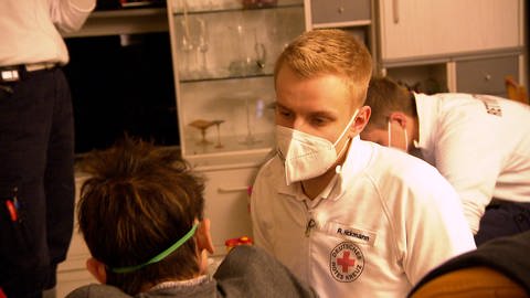 Ein Notfallsanitäter mit Atemmaske kümmert sich um eine Patientin. Beim DRK in Tübingen ist Notfallsanitäter Robert Hickmann im Einsatz. Hier betreut er eine Frau mit Atemnot.  (Foto: SWR)