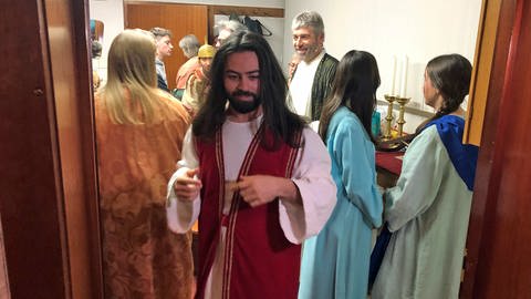 Mann mit langem schwarzen Haaren und Bart in rotem Gewand. Der "syrische Jesus" ist für den Auftritt in ein traditionelles orientalisches Gewand gekleidet. (Foto: SWR, Frank Polifke)