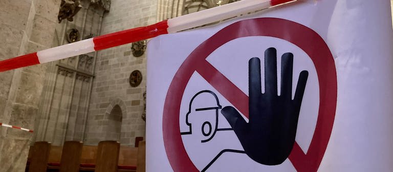 Ein Warnschild weist Besucher darauf hin, dass bestimte Bereiche im Ulmer Münster gesperrt sind. Denn in der Kirche bröckelt Putz von der Decke.  (Foto: SWR, Anja Müller )