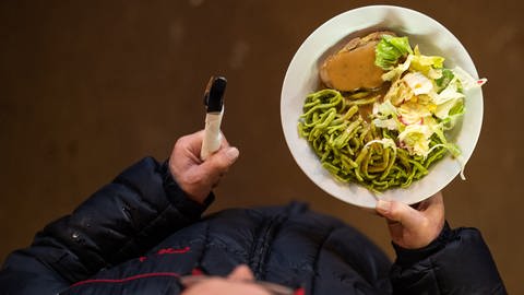 Ein Mann geht mit einem Teller Essen durch die Kirche (Symbolbild) (Foto: dpa Bildfunk, picture alliance/Sebastian Gollnow/dpa)