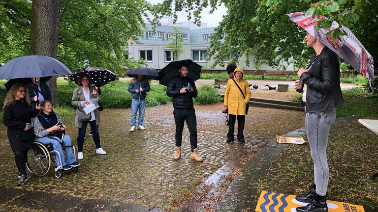 Oberbürgermeisterin Katrin Albsteiger steht auf dem Podest der Speakers' Corner unter einem Schirm im Regen, vor ihr mehrere Zuhörer. Die Speakers Corner in Neu-Ulm ist eröffnet. (Foto: SWR, Isabella Hafner)