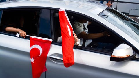 Ein Auto, aus dem türkische Fahnen hängen. Bei einem Autokorso in Ulm nach dem Wahlsieg des türkischen Präsidenten Erdogan hat die Polizei mehrfach eingegriffen. Einige Teilnehmende werden angezeigt.(Sujetbild) (Foto: IMAGO, Imago)