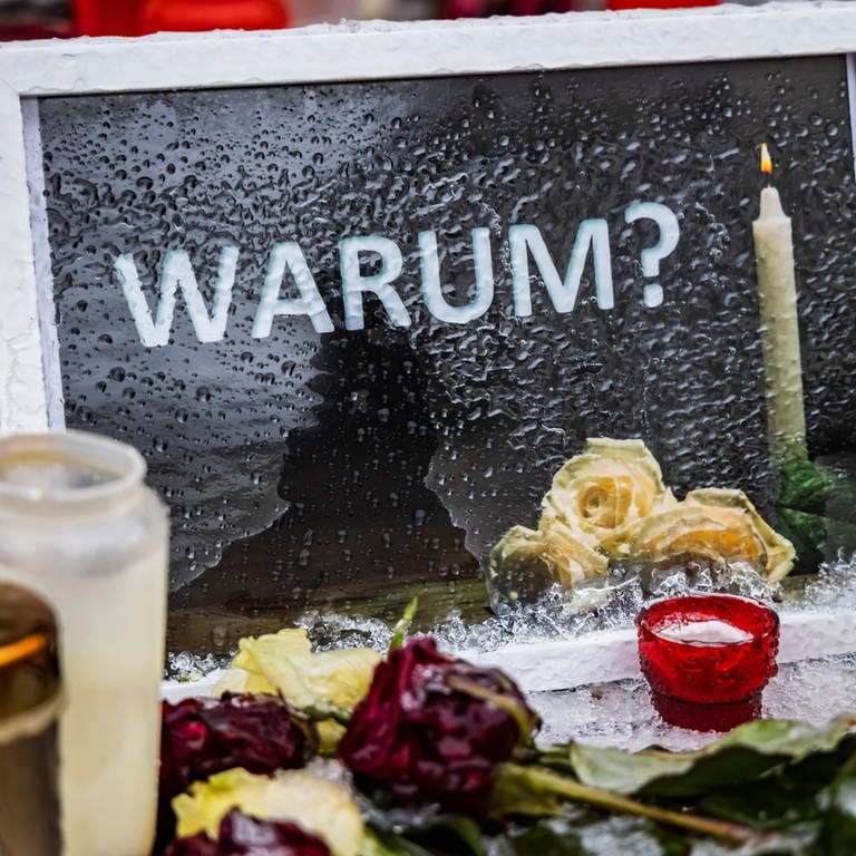 Am Tatort in Illerkirchberg haben Passanten Kerzen, Blumen und einen Bilderrahmen mit dem Wort "Warum?" abgelegt. (Archivbild) (Foto: IMAGO, IMAGO / Arnulf Hettrich)