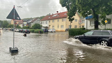 Ein Auto fährt langsam über eine überflutete Straße. Nach dem Unwetter mit Hagel und Starkregen "schleicht" ein Auto durch die Wassermassen im Lehrer Tal in Ulm.  (Foto: SWR, Maja Nötzel)
