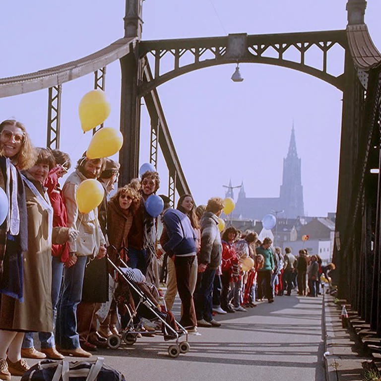 Die Menschenkette im Herbst 1983 gegen atomare Aufrüstung reichte auch über die König-Wilhelm-Brücke in Ulm: Viele Menschen reichten sich die Hände, manche hatten Luftballons dabei. Im Hintergrund sieht man das Münster in Ulm (Foto: SWR)