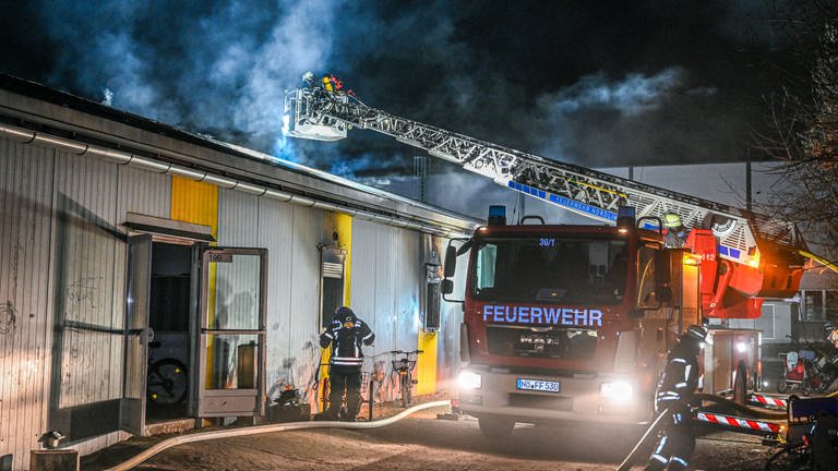 Mitarbeiter der Feuerwehr löschen einen Brand in einer Asylbewerberunterkunft in Nördlingen. (Foto: dpa Bildfunk, picture alliance/dpa | Marius Bulling)