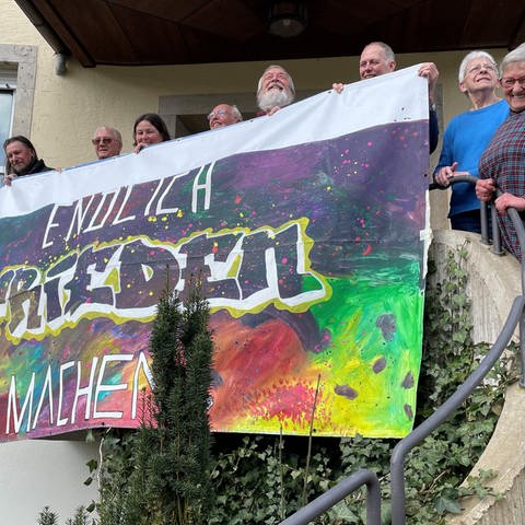 Mitglieder des Aktionsbündnisses in Ellwangen zeigen ein buntes Transparent mit der Aufschrift "Frieden machen!" und sind bereit für den Ostermarsch 2024. (Foto: SWR)