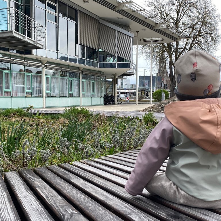 Das 9-Monate alte Pflegekind sitzt auf einer Bank vor dem Landratsamt des Alb-Donau-Kreises. (Foto: SWR, Maja Nötzel)