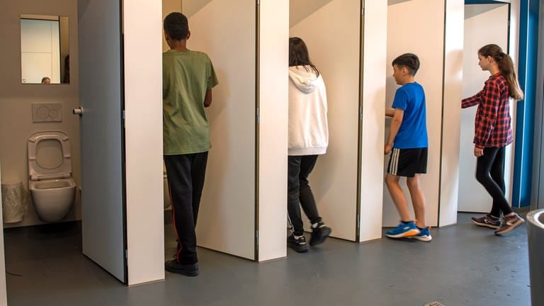 Jungen und Mädchen gehen in eine Unisextoilette an der Sägefeldschule in Ulm-Wiblingen. Bei der Sanierung der Toilettenanlage an der Werkrealschule wurde die Geschlechtertrennung aufgehoben. (Foto: dpa Bildfunk, picture alliance dpa  Stefan Puchner)