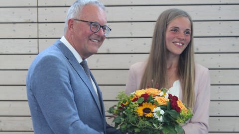 Ein Mann übergibt einen großen Blumenstrauß an eine junge Frau: Anna-Lisa Bohn wird neue Bürgermeisterin von Ellenberg (Foto: Privat)