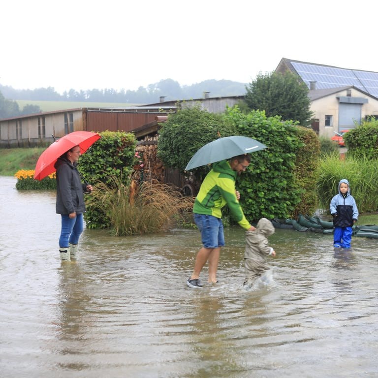 Kinder plantschen in einer riesigen Pfütze. Hochwasser nach Starkregen im Alb-Donau-Kreis in Schnürpflingen und Staig (Foto: Ralf Zwiebler)