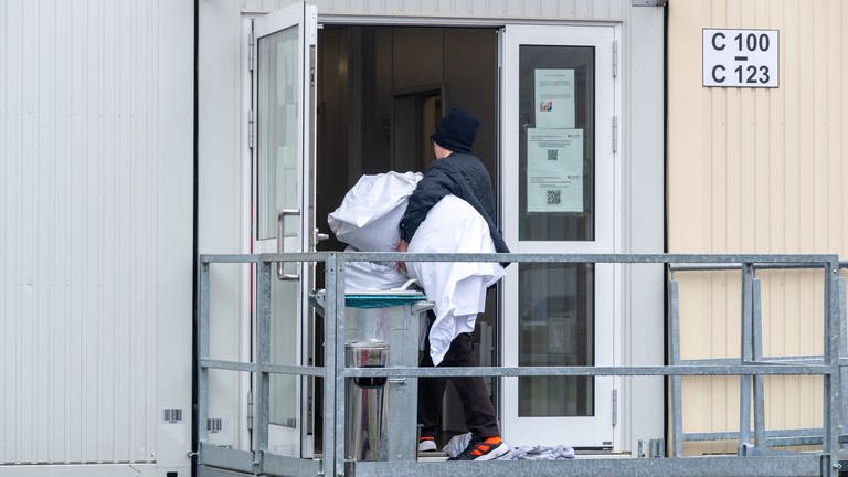 Ein Mann bringt Bettwäsche in einen Container. In Blaustein Herrlingen sollen in einer solchen Unterkunft 100 bis 200 Geflüchtete Platz finden. (Symbolbild)