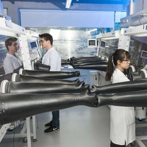 Aufbauten in einem Labor mit Forscherinnen und Forscherin. Im Helmholtz-Institut in Ulm wird nach Alternativen für Lithium-Ionen-Batterien gesucht.  (Foto: Pressestelle, Helmholtz-Institut Ulm)