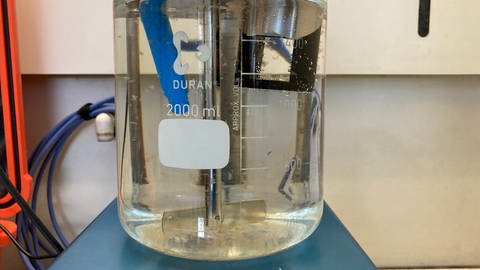 Ein Rührer verwirbelt die Aluminiumpartikel in einem Behälter mit Donauwasser. Schwebstoffe sollen daran haften und auf diese Weise aus dem Wasser gefiltert werden. (Foto: SWR)
