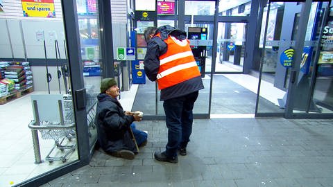 Ein DRK-Mitarbeiter reicht einem Obdachlosen in einer Passage in Ulm eine warme Suppe. Der Ulmer Kältebus ist derzeit jeden Abend unterwegs, um Wohnungslosen zu helfen.  (Foto: SWR, Stefanie Schmitz)