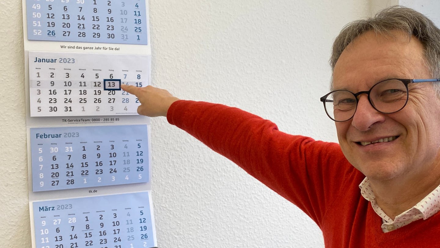 Prof. der Aktuarwissenschaften an der Uni Ulm zeigt lachend im Kalender auf Freitag, 13. (Foto: SWR, Frank Wiesner)