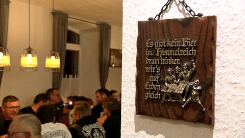 Ein vollbesetzter Gasttisch im Gasthaus Kanne in Heidenheim, daneben ist ein als Wandschmuck dienender Bier-Trinkspruch zu sehen . Nach 20 Jahren wurde das Gasthaus Kanne in Heidenheim wieder eröffnet. (Foto: SWR, Stefanie Schmitz)