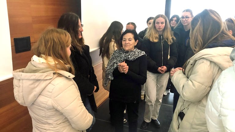 Eine ältere Frau in einer Gruppe von Schülerinnen. Die Zeitzeugin Eva Erben berichtete an der Hochschule Aalen vor Schülern und Studierenden über den Holocaust. (Foto: SWR, Frank Polifke)