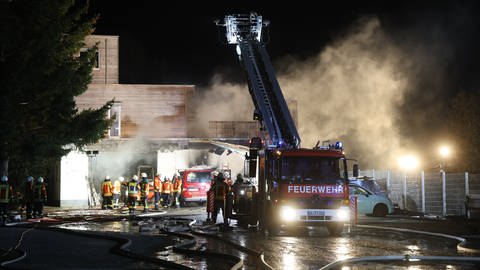Feuerwehrleute und -fahrzeug vor einem brennenden Gebäude. Die Feuerwehr war am späten Dienstagabend wegen eines Brandes in einem Dachdeckerbetrieb in Laichingen (Alb-Donau-Kreis) im Einsatz. (Foto: z-media, Ralf Zwiebler)