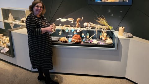 Urmu-Chefin Stefanie Kölbl vor den organischen Materialien und "Nachbauten" von Urzeit-Werkzeugen und Kleidung