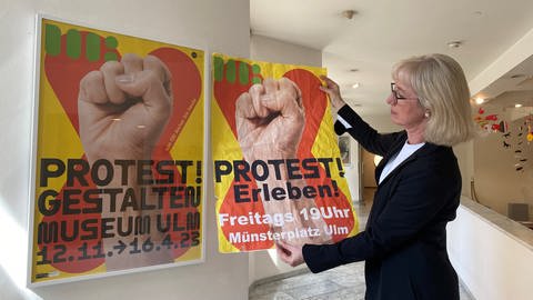 Museumsleiterin Stefanie Dathe hängt ein "echtes" Plakat ihrer Ausstellung zum Thema "Protest" auf.  (Foto: SWR)