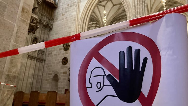 Ein Warnschild weist Besucher darauf hin, dass bestimte Bereiche im Ulmer Münster gesperrt sind. Denn in der Kirche bröckelt Putz von der Decke.  (Foto: SWR, Anja Müller )