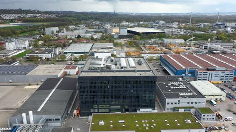 Ein hoher, grauer Neubau in einem Industriegebiet. Wie am Horizont das Ulmer Münster: Die Inbetriebnahme des Teva-Neubaus Genesis (unten im Bild) ist in Sichtweite.  (Foto: SWR)