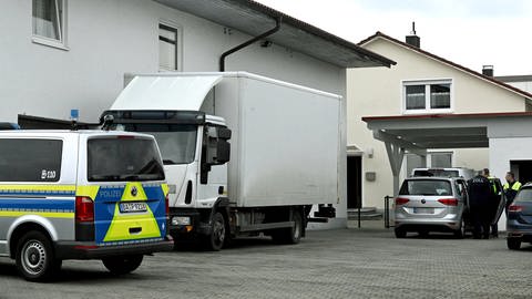 Kräfte von Zoll und Polizei hinter einer Schranke auf einem Firmengelände. Bei einer Razzia unter anderem in Krumbach (Kreis Günzburg) wurden fünf Personen festgenommen. (Foto: Thomas Heckmann)