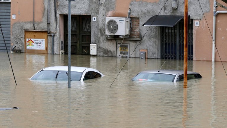 Autos stehen auf einer überschwemmten Straße im Wasser. In der italienischen Region Emilia-Romagna ist es nach heftigen Regenfällen zu teils dramatischen Überschwemmungen gekommen (Foto: dpa Bildfunk, picture alliance/dpa | Michele Nucci)