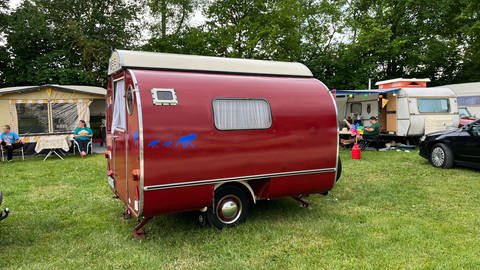 Die "Knospe", ein weinroter Wohnwagen-Oldtimer aus dem Jahr 1965, lässt sich für die Fahrt eng zusammenfalten und bei Benutzung wieder öffnen. Zu sehen ist er auf dem Campingplatz Heidehof in Laichingen.