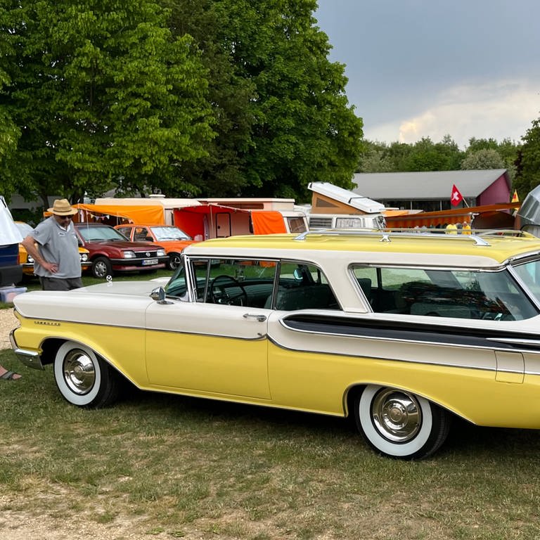 Auch amerikanische Oldtimer sind derzeit auf dem Campingplatz Heidehof in Laichingen zu sehen. Ein schnittiger gelb-weißer Wagen und im Hintergrund ein Wohnwagen in abgerundeter Form aus Aluminium.