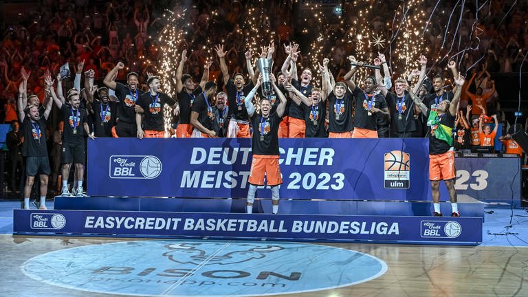 Die Meisterschaft in der Tasche. Den Pokal in der Hand: Der Ulmer Basketballer Thomas Klepeisz beim Meisterbild. (Foto: IMAGO, IMAGO | Langer)
