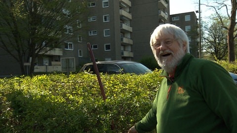 Mann lacht beim Kehren auf einem Parkplatz. Hat sichtlich Spaß bei der Kehrwoche: Hans-Peter Zagermann, Hausbewohner und Initiator des Kampfs für die Kehrwoche und die gemeinsame Großputzaktion. (Foto: SWR, Frank Wiesner)