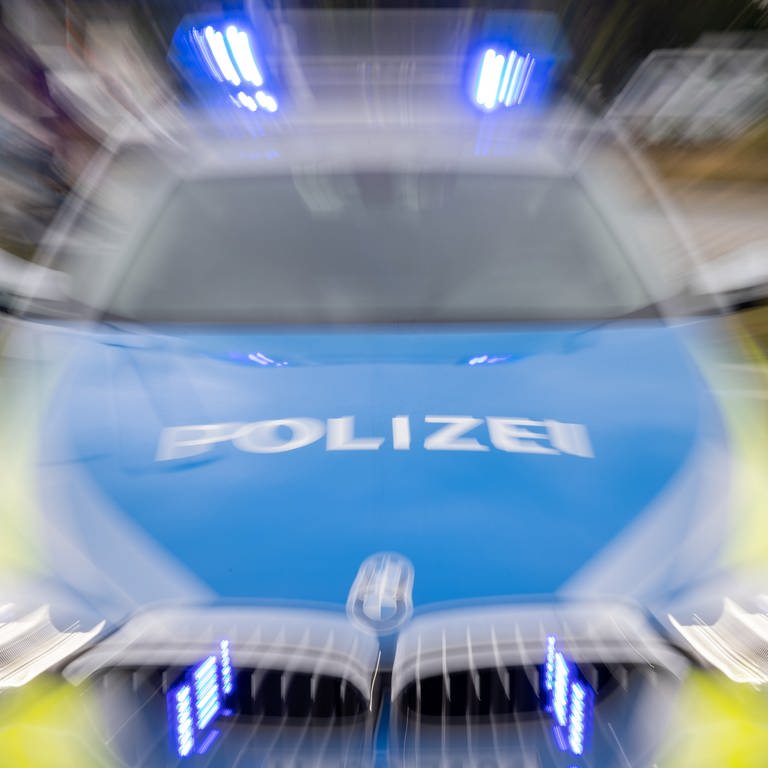 Die verschwommene Front eines Poilzeiautos mit eingeschaltetem Blaulicht: Ein betrunkener Autofahrer ist der Polizei auf der B29 bei Heubach nur aufgefallen, weil er einen waghalsigen Fluchtversuch unternommen hat. (Foto: dpa Bildfunk, picture alliance/dpa | Daniel Karmann)