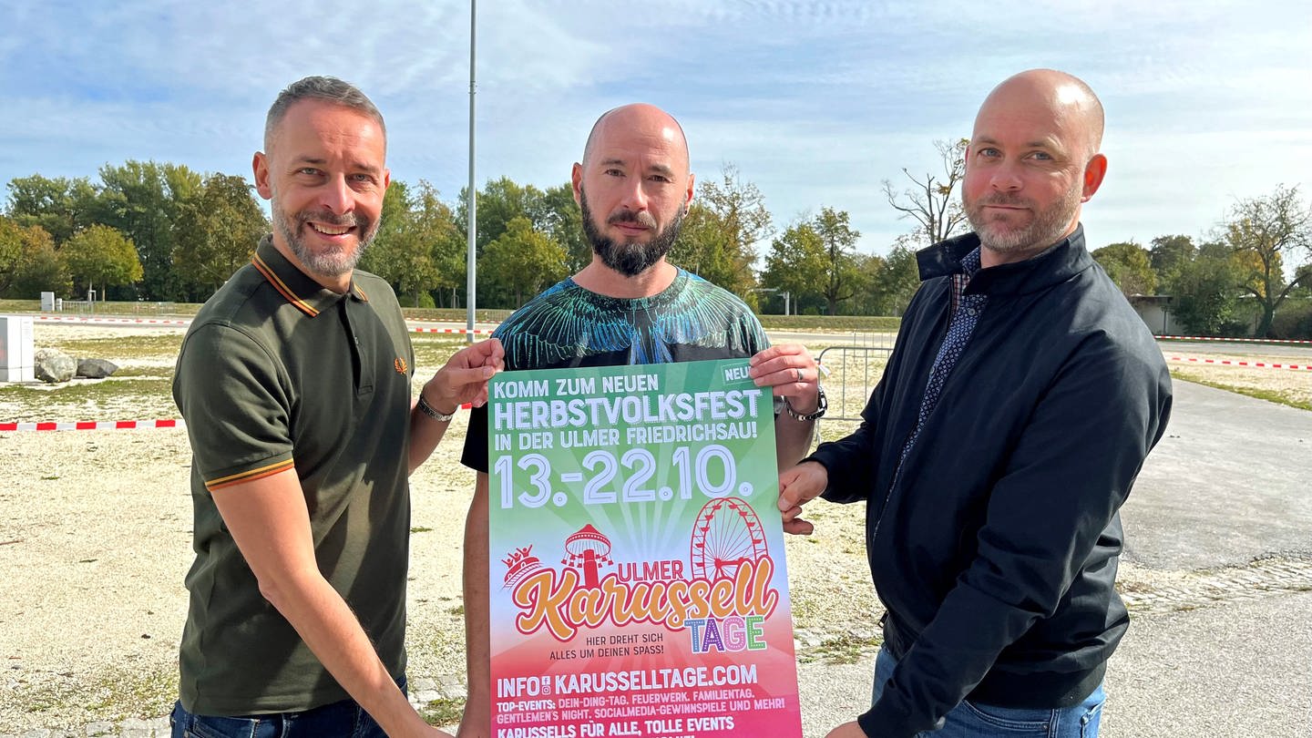 Drei Männer halten ein Plakat: Auf dem Festplatz in Ulm finden im Oktober  die 1. Ulmer Karusseltage statt (Foto: SWR, Jorina Stuber)