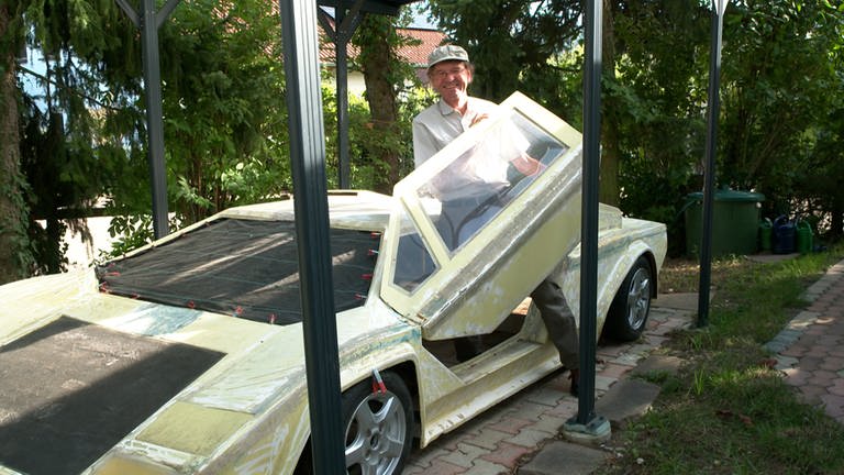 Modelbauer Friedrich Kitzsteiner öffnet die Flügeltüren an seinem noch nicht fertig gestellten, ferngesteuerten Lamborghini im Ma?stab 1:1.
