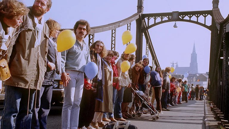 Die Menschenkette im Herbst 1983 gegen atomare Aufrüstung reichte auch über die König-Wilhelm-Brücke in Ulm: Viele Menschen reichten sich die Hände, manche hatten Luftballons dabei. Im Hintergrund sieht man das Münster in Ulm (Foto: SWR)