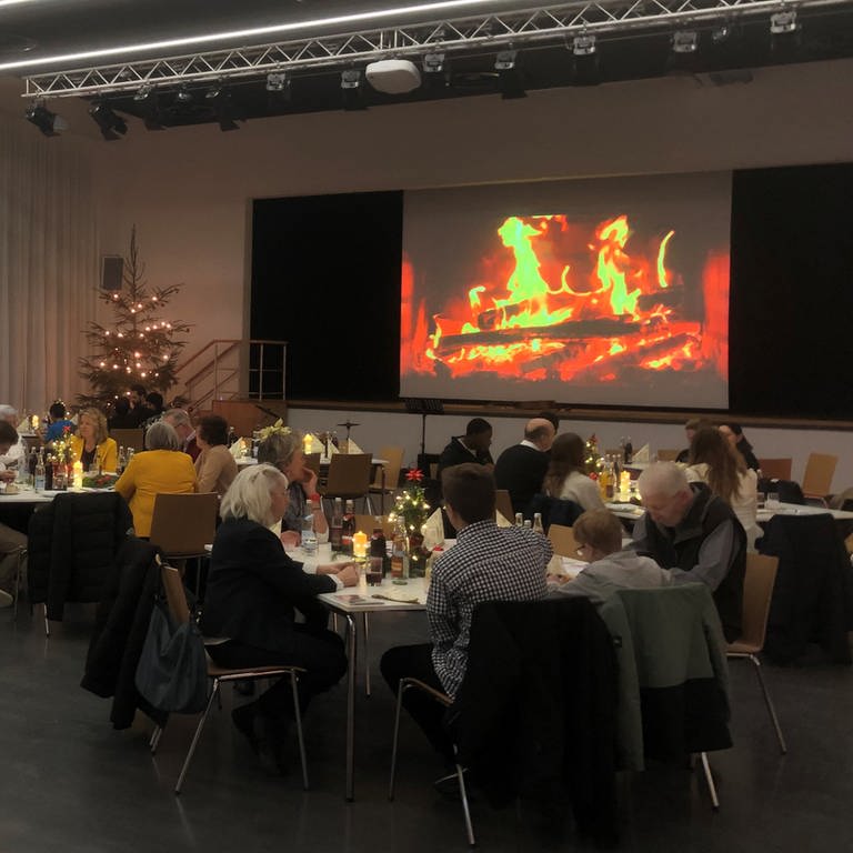 An gemütlichen Tischen in der Stadthalle Heubach feiern Menschen Heiligabend gemeinsam statt einsam (Foto: Nils Dollinger, BeRo, Begegnung unterm Rosenstein)