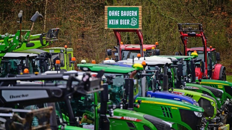 Eine Reihe von Traktoren, darüber ein Schild  "Ohne Bauern kein Bier". Der Aalener Löwenbräu-Chef hat Bundeslandwirtschaftsminister Cem Özdemir (Grüne) ausgeladen, "aus Solidarität mit der heimischen Landwirtschaft", heißt es in einer Mitteilung des Unternehmens. Die  jüngst in Berlin vereinbarten Sparpläne der Ampelregierung zur Abschaffung der Agrardiesel-Subventionen und der Kfz-Steuerbefreiung träfen die Landwirtschaft "unangemessen hart", heißt es dazu weiter. (Foto: dpa Bildfunk, Picture Alliance)