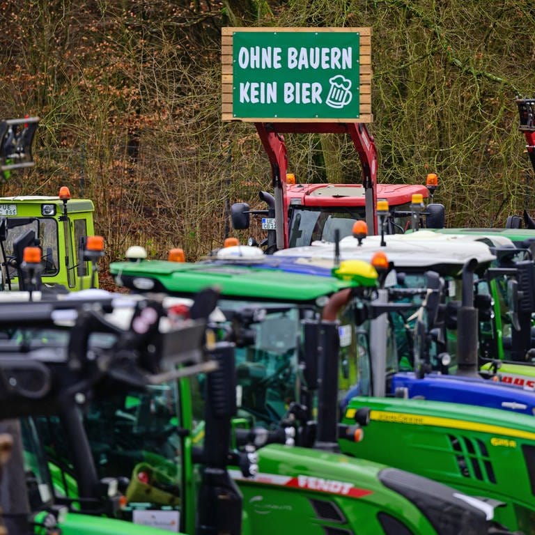 Eine Reihe von Traktoren, darüber ein Schild  "Ohne Bauern kein Bier". Der Aalener Löwenbräu-Chef hat Bundeslandwirtschaftsminister Cem Özdemir (Grüne) ausgeladen, "aus Solidarität mit der heimischen Landwirtschaft", heißt es in einer Mitteilung des Unternehmens. Die  jüngst in Berlin vereinbarten Sparpläne der Ampelregierung zur Abschaffung der Agrardiesel-Subventionen und der Kfz-Steuerbefreiung träfen die Landwirtschaft "unangemessen hart", heißt es dazu weiter.