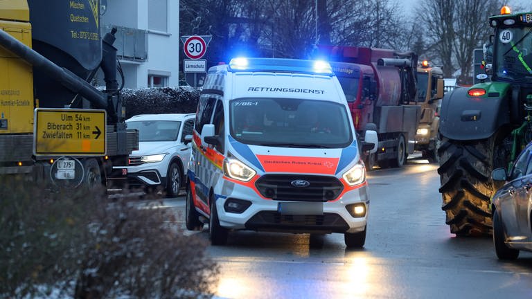 In Riedlingen (Kreis Biberach) fährt ein Krankenwagen des Rettungsdienstes mit eingeschaltetem Blaulicht während des Bauernprotests durch eine im Stau gebildete Rettungsgasse.
