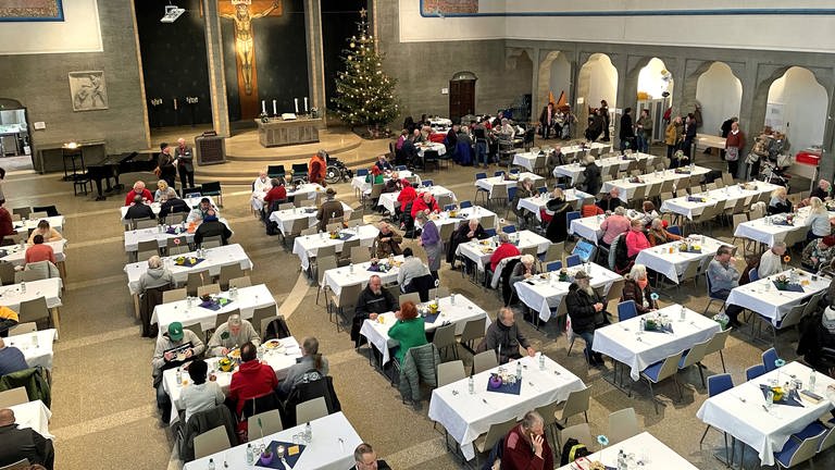 Menschen sitzen an gedeckten Tischen im Kirchenschiff der Pauluskirche: Hier hat am Donnerstag die 29. Vesperkirche begonnen. Vier Wochen lang erhalten Bedürftige eine warme Mahlzeit. 