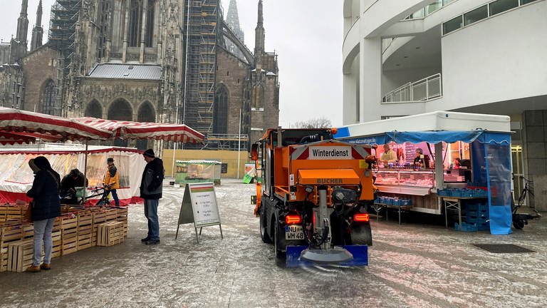 Winterdienstfahrzeug auf einem Wochenmarkt. Folgen des Eisregens: Nur wenige Stände waren beim Wochenmarkt auf dem Ulmer Münsterplatz aufgebaut - und der Winterdienst streute noch einmal kräftig nach. 