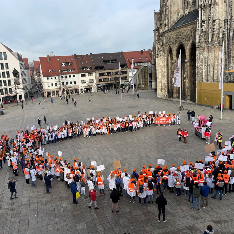 Rund 170 Ärztinnen und Ärzte haben nach Angaben der Uniklinik Ulm am Dienstagnachmittag für bessere Arbeitsbedingungen demonstriert. Bei einer Kundgebung auf dem Münsterplatz kritisierten sie vor allem die hohe Arbeitsbelastung. (Foto: SWR, Laura Scheibling)