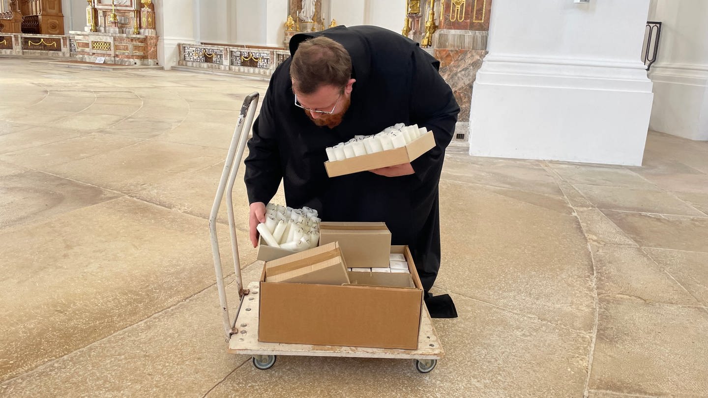 Bruder Matthias sammelt ausgediente Kerzen im Kloster Neresheim und stellt auf einen Wagen. Das Wachs der Kerzhen wird in die Ukraine gebracht, wo es dann zu Büchsenlichtern weiterverarbeitet wird. (Foto: SWR)