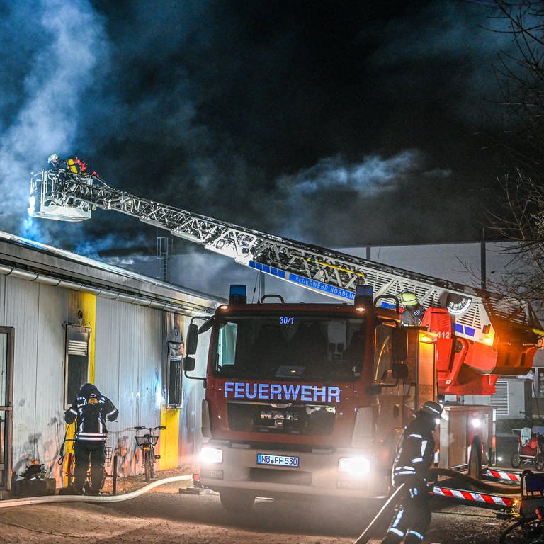 Mitarbeiter der Feuerwehr löschen einen Brand in einer Asylbewerberunterkunft in Nördlingen.