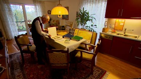 Helmut Weiss, 95 Jahre alt, steht an seinem Esstisch und blättert im Fotoalbum der Familie. (Foto: SWR, Frank Wiesner)