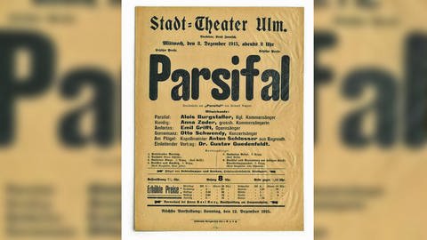 Schwarze Schrift auf vergilbtem Papier - ein historisches Plakat von 1915. Es ist die Ankündigung zweier Konzerte am damaligen Stadt-Theater Ulm mit Gesang und der Musik aus Wagners "Parsifal".