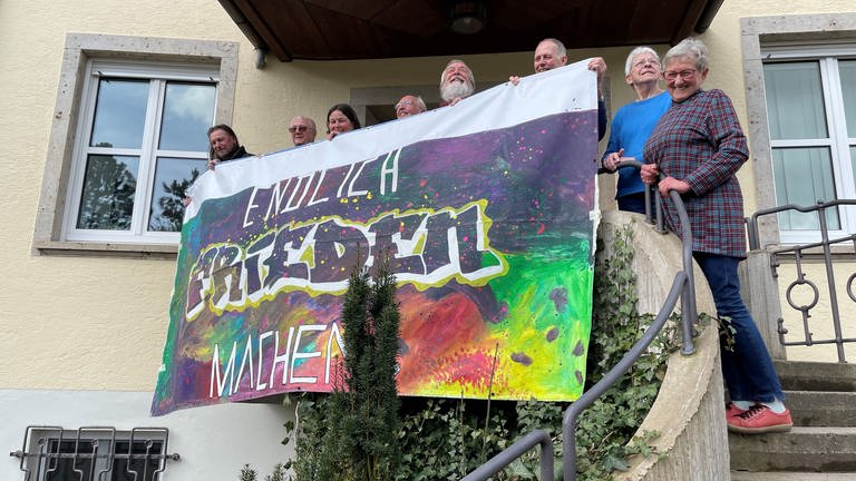 Mitglieder des Aktionsbündnisses in Ellwangen zeigen ein buntes Transparent mit der Aufschrift "Frieden machen!" und sind bereit für den Ostermarsch 2024.